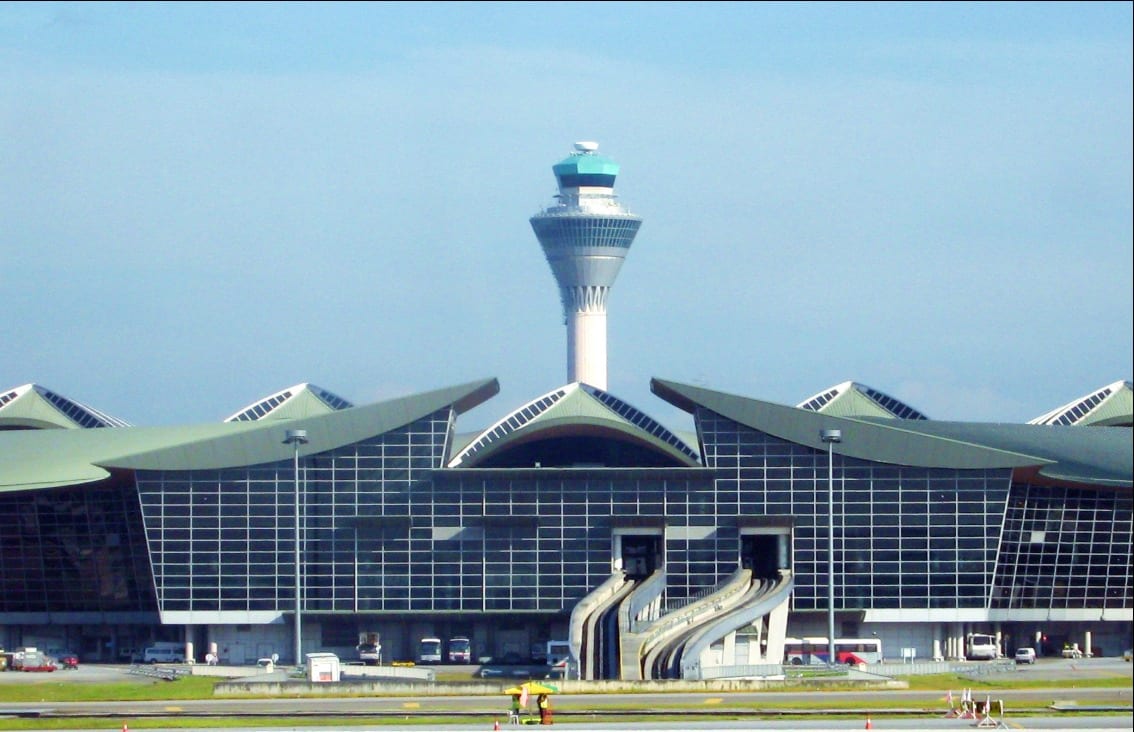 Modern Kuala Lumpur International Airport terminal building with control tower against clear blue sky